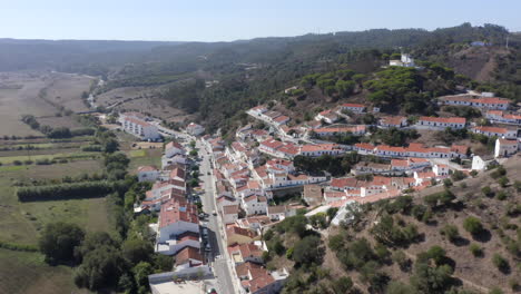 aerial drone flight towards the hills with view of city in aljezur, algarve, portugal