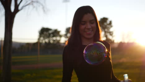 mujer hispana de ensueño soplando burbujas de ensueño al aire libre al atardecer con el sol y el destello de la lente