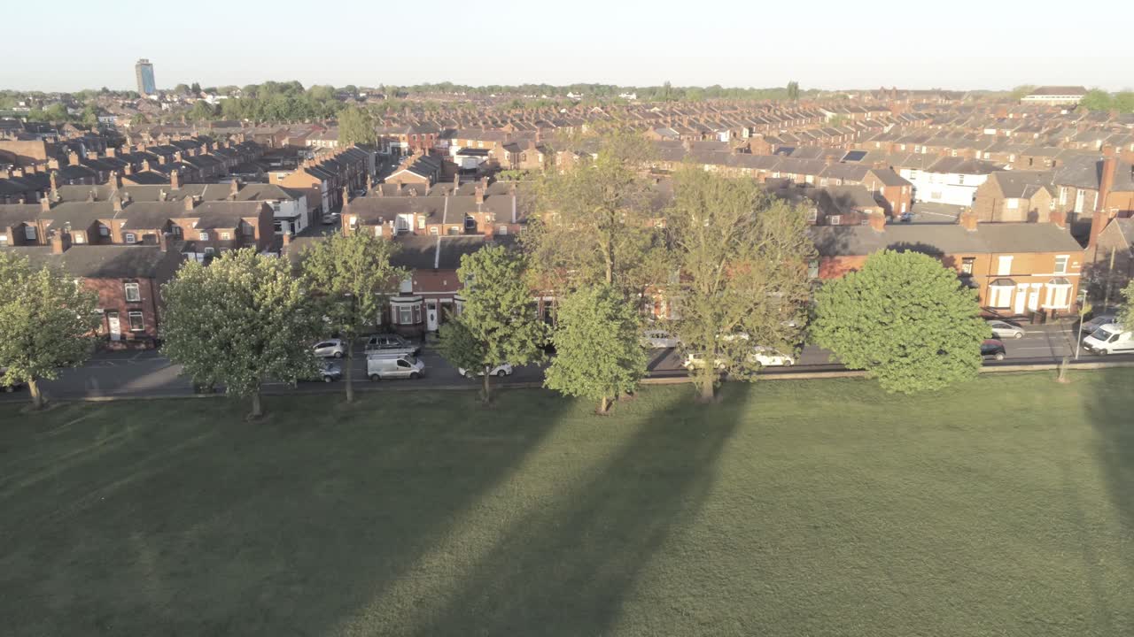 Drone aerial view across British typical residential housing estate descending to park