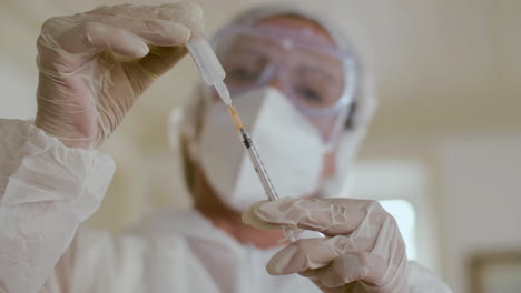 close-up shot of doctor drawing vaccine into syringe