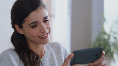 mujer hermosa usando un teléfono inteligente viendo entretenimiento en línea leyendo mensajes de redes sociales relajándose en casa disfrutando de la tecnología móvil