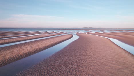 Fliegen-über-Wellenwellen-Mit-Wasser-Auf-Den-Lücken-Bei-Ebbe-Im-Sommer