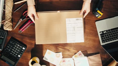 e-commerce storage shop, woman packing goods and clothes for second hand delivery market, dedicated packaging and shipping workspace with supplies and technology for efficiency, online sales.