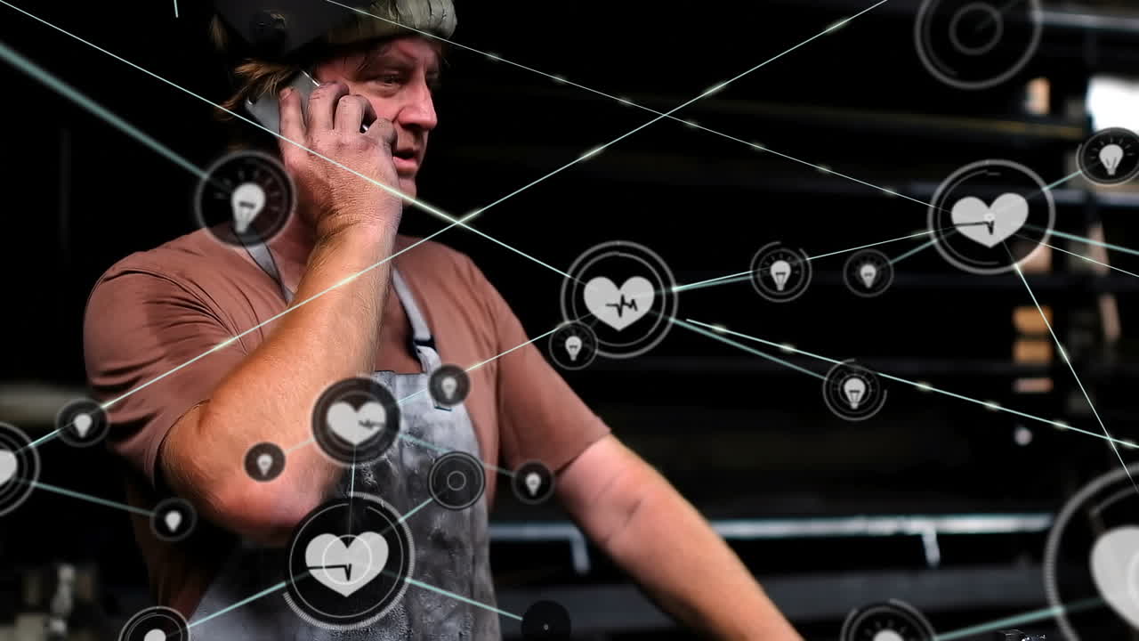 animación de una red de iconos digitales sobre un trabajador caucásico hablando con un teléfono inteligente en una fábrica