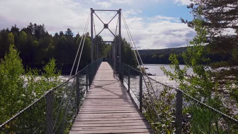 pan beautiful view of a calm river surrounded by lush greenery with bridge over it