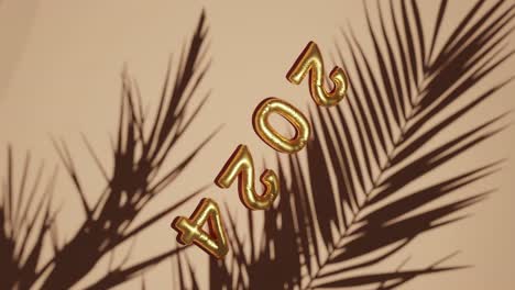 golden ballon 2024 on silhouetted palms brown background vertical