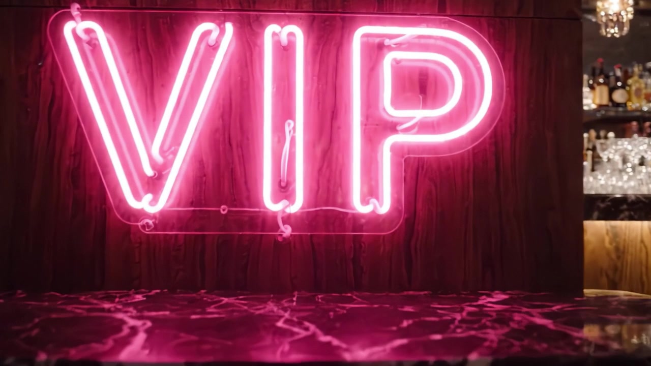Lounge VIP lussuosa con mobili eleganti e insegna al neon in un ambiente da bar sofisticato, perfetta per incontri e celebrazioni esclusive.