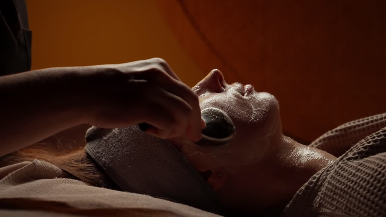 Kvinde får afslappende ansigtsmassage med iskugler i spa