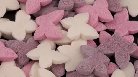 pile of small butterfly shaped rose, white and purple candies rotating.