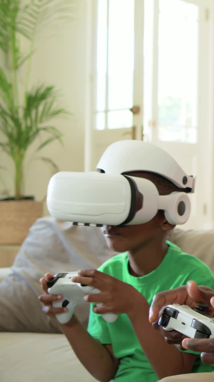 Video verticale: Inizio di un gioco VR, bambino con visore che usa un controller sul divano, mentre un adulto ne tiene un secondo.