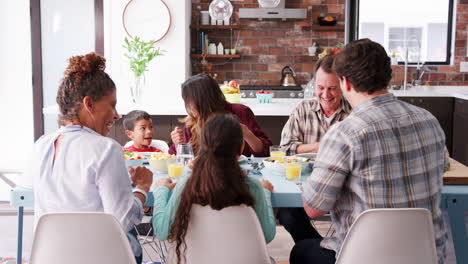 Familia-Multigeneracional-Orando-Antes-De-Comer-Alrededor-De-La-Mesa-En-Casa