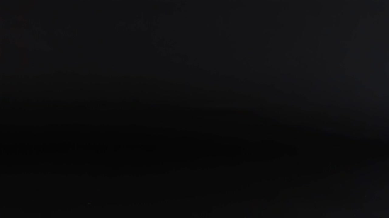 A blue tennis ball captured in mid-air against a dark background, showcasing its motion.