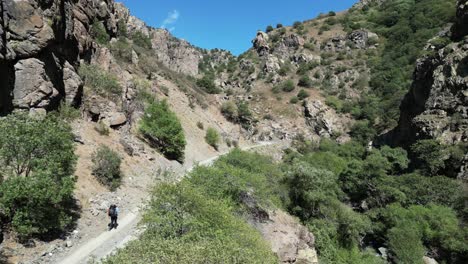 Aerial:-Lone-backpacker-walks-up-narrow-canyon-road-in-rural-Armenia