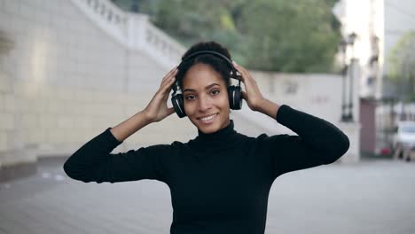 Glückliche-Frau-Trägt-Kabellose-Kopfhörer-Und-Hört-Musik-Im-Freien-Auf-Einer-Leeren-Straße-1