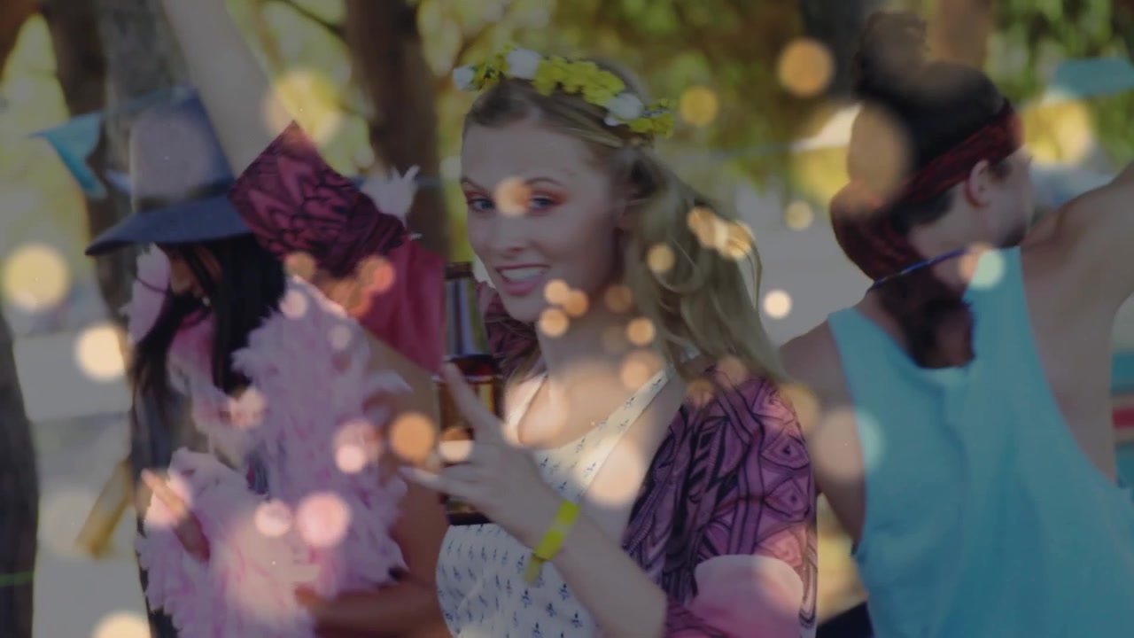 Mujer con corona floral y amigos bailando, con un efecto bokeh superpuesto, levantando botellas en celebración.
