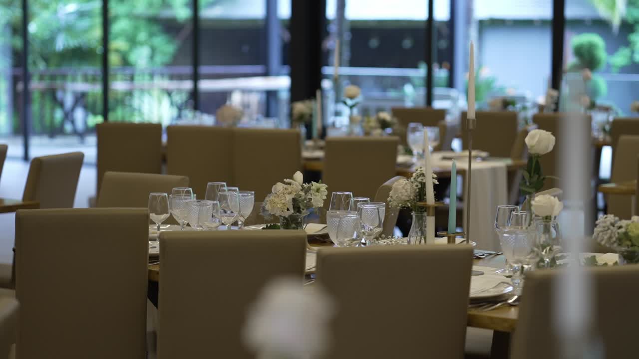 Wedding reception tables with glassware, candles, and floral arrangements in an elegant venue