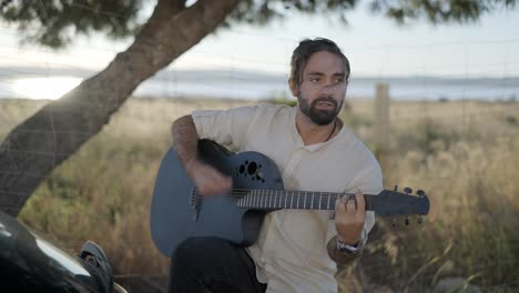 hombre tocando la guitarra acústica al aire libre