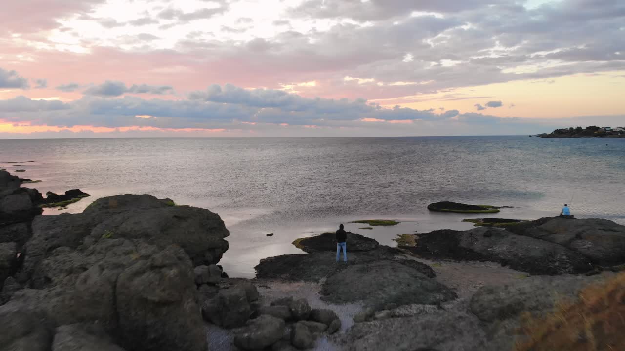 불가리아, 마름모꼴 근처 바다의 바위에서 일출을 즐기는 한 젊은이 위에 무인 항공기에서 공중 촬영