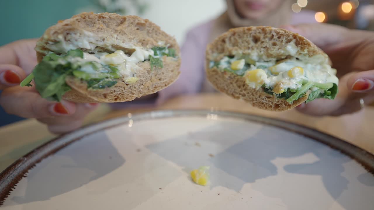 mujer sosteniendo un delicioso sándwich con maíz y ensalada