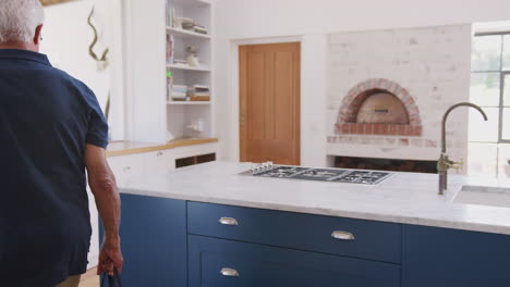 senior couple returning home from shopping trip carrying reusable shopping bags through kitchen