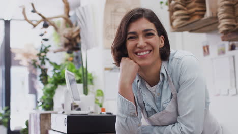 retrato de una asistente de ventas de sexo femenino sonriente de pie detrás del mostrador de ventas de la tienda de flores