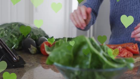 animación de corazones sobre el hombre caucásico cocinando y usando la tableta