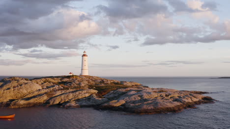 Lille-Torungen-Lighthouse-with-Wooden-Boat-in-front-Of-The-Island-Of-Arendal-Torungen,-Norway