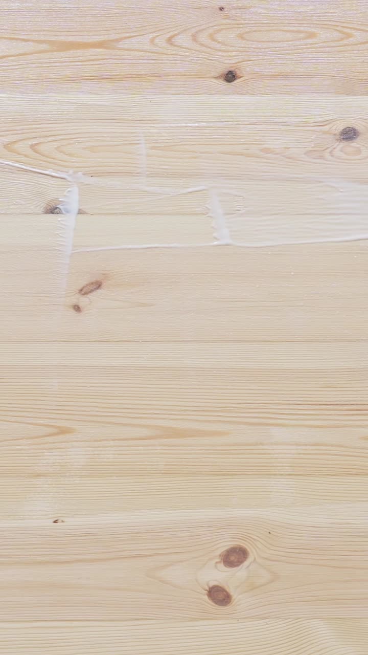 Detailed vertical close-up of varnishing a hardwood floor during a DIY home renovation