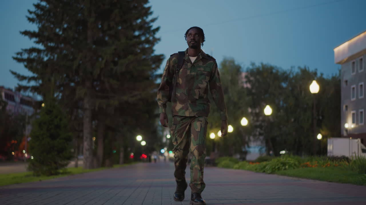 Soldier Maintains Vigilant City Watch, Military Personnel Patrol City Walkway Calmly, Disciplined Military Officer Conducts Steady Patrol Under Street Lamps Amidst Evening City Traffic