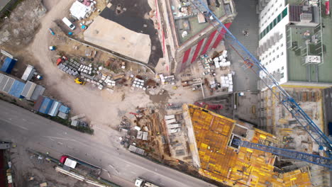 top down aerial - zoom in on the construction site of a skyscraper - close to a construction crane - formworks on the construction site - high-engineering construction in the city center