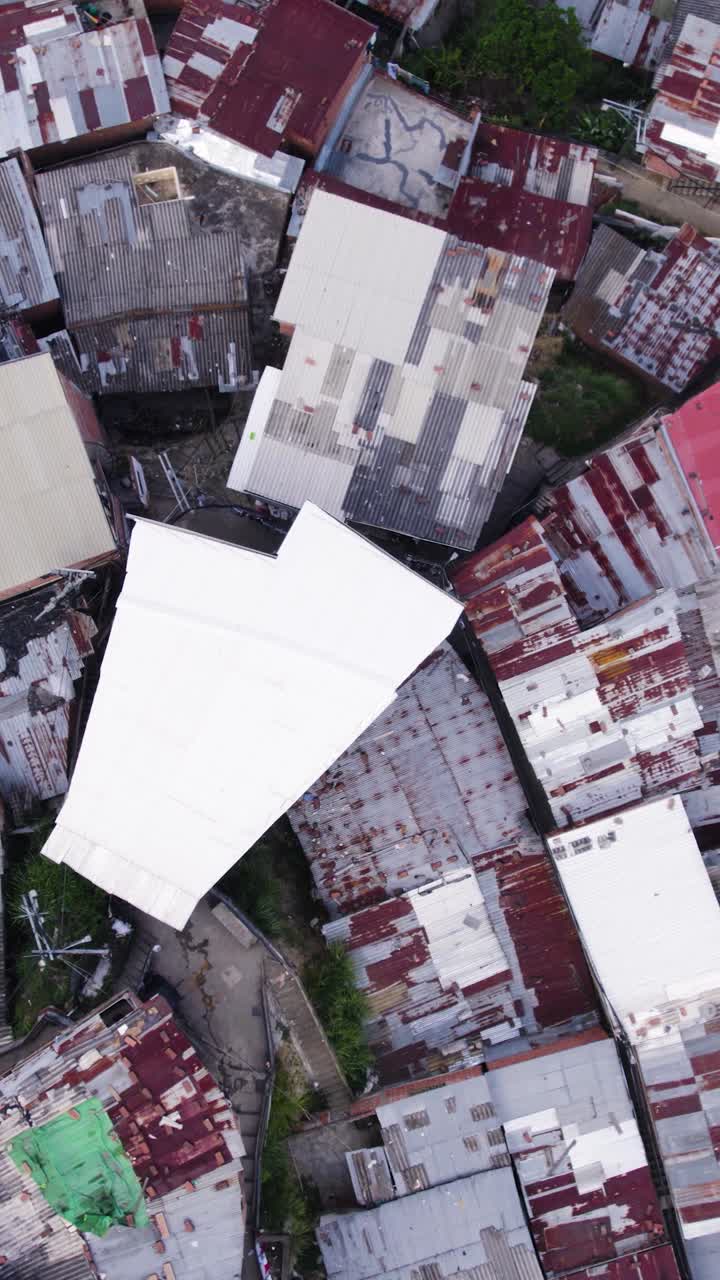 Drone shot capturing the vibrant, densely packed houses and rooftops of Comuna 13, also known as San Javier, in Medellin. vertical video, rising shot