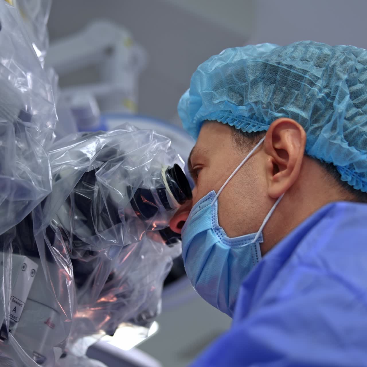 Medico attento e concentrato che guarda nel binocolo e dice qualcosa. Attrezzatura moderna rivestita in plastica. Vista dal basso
