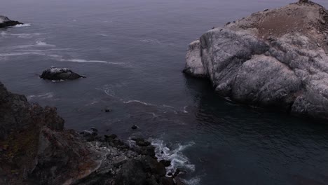 aerial shot pushing towards rocks off the coast of big sur, california