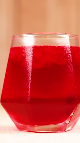 red drink in geometric glass on wooden table