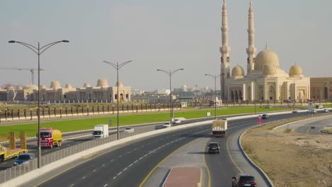 city road with different vehicles traveling near al qasimia university mosque in sharjah, united arab emirates