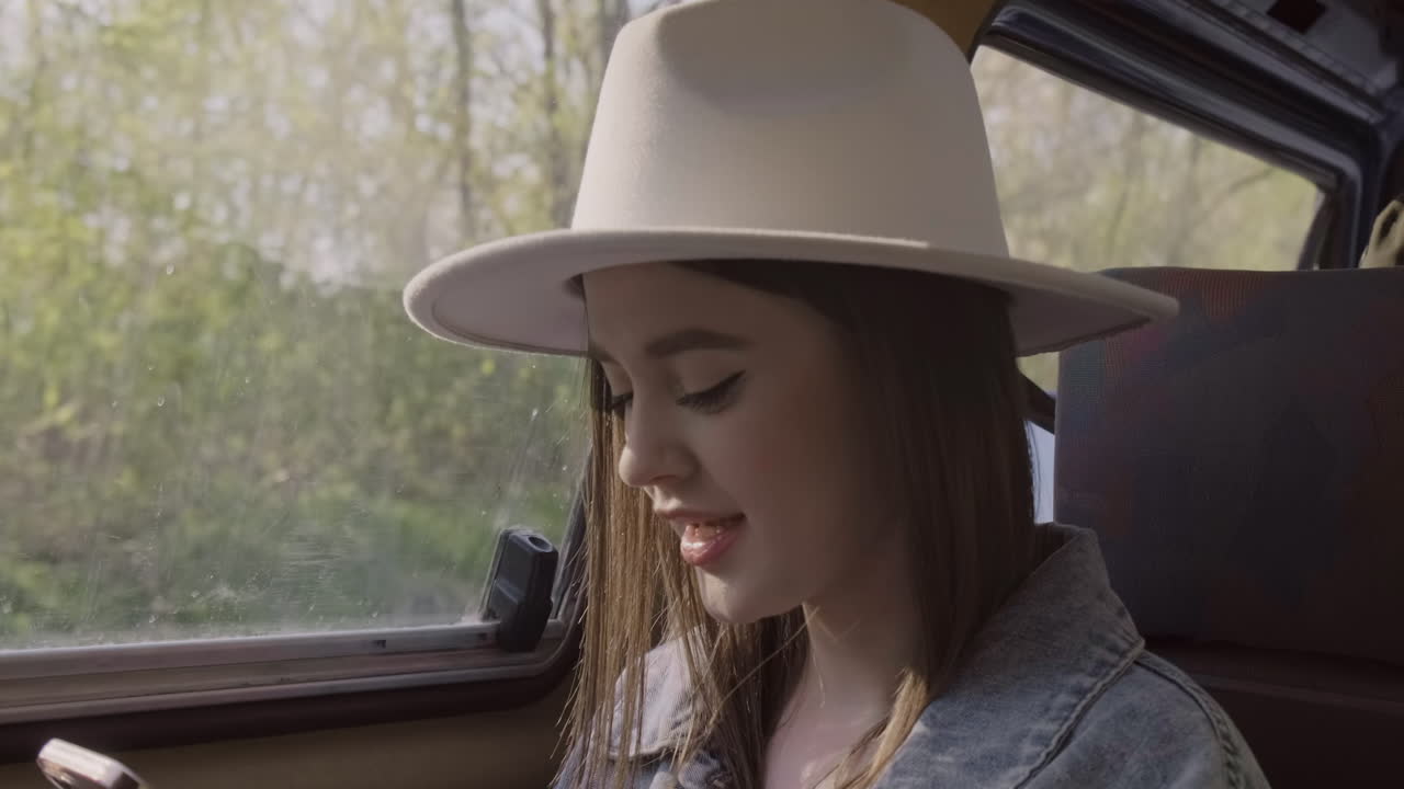 una hermosa joven escribiendo en su teléfono celular mientras sonríe durante un viaje por carretera en la caravana 1