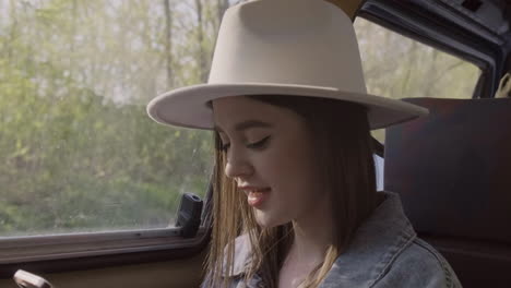 Una-Hermosa-Joven-Escribiendo-En-Su-Teléfono-Celular-Mientras-Sonríe-Durante-Un-Viaje-Por-Carretera-En-La-Caravana-1