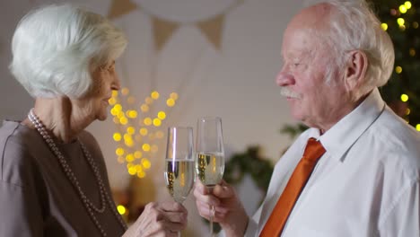 elegante pareja de ancianos brindando con champán durante la víspera de año nuevo en casa