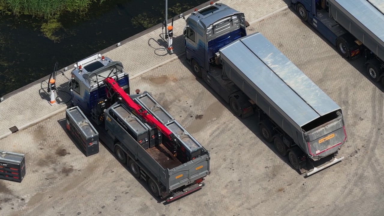 Aerial view of electric trucks with mobile battery units used for charging vehicles in the field, showing fleet electrification, energy storage and sustainable transport technology.