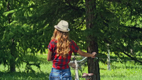 woman carries a bicycle walking in the forest, it is reached by a man riding a bicycle and they talk