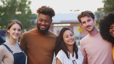 Six-millennial-hipster-friends-standing-in-a-city-street-smiling-to-camera,-panning-shot