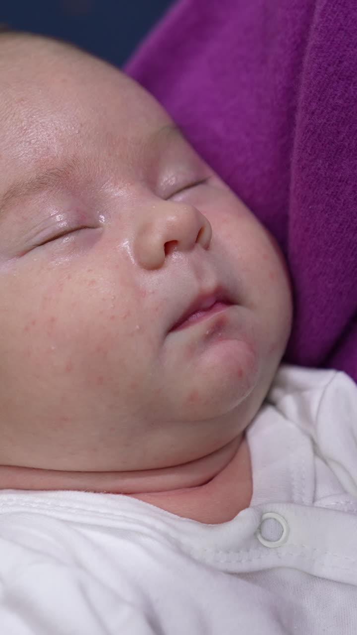 Loving and caring mother is hugging her infant baby son. Mother is rocking her baby while the child sleeping peacefully. Close up. Vertical video