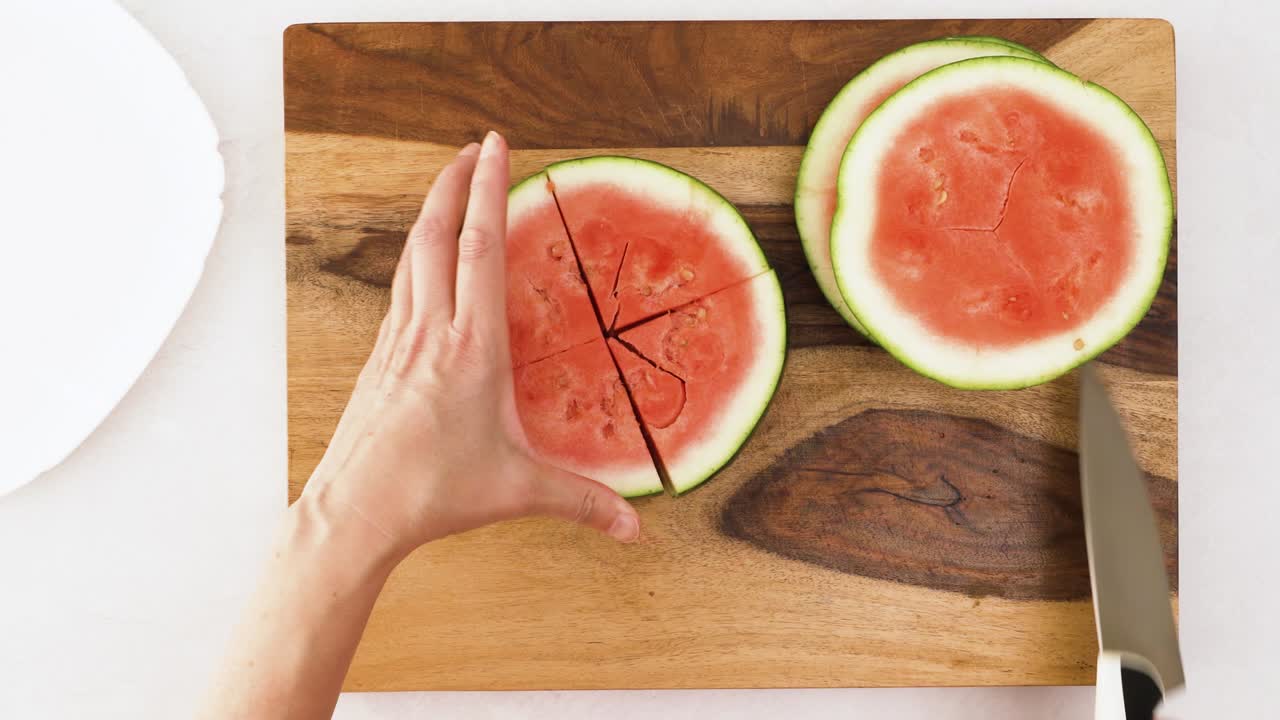 mujer corta sandía en una tabla de cortar de madera, vista de cerca desde arriba