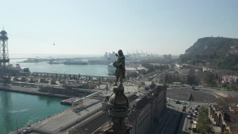 Fly-around-person-standing-on-high-column.-Statue-on-Columbus-Monument-and-cityscape-in-background.-Barcelona,-Spain