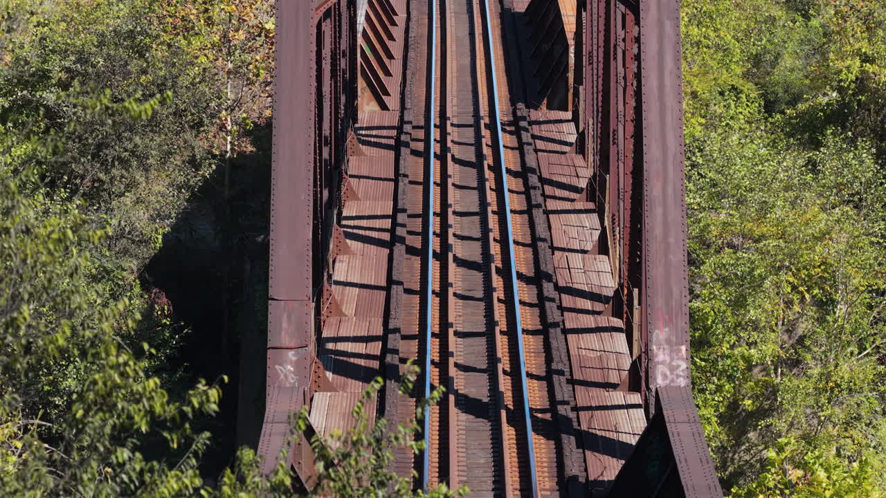 Aerial View Tilting Up Over Rusty Train Bridge and Tracks