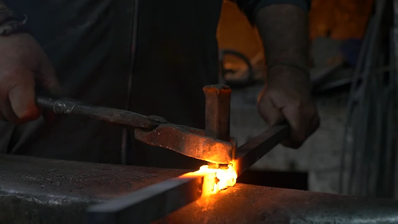 A blacksmith beats red-hot metal on the anvil
