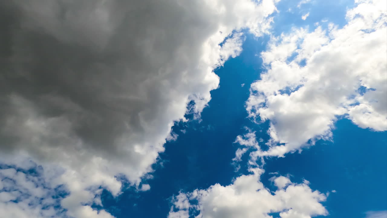 Cumulus clouds floating by the bright blue sky. White and grey clouds fully covering the horizon. Timelapse.