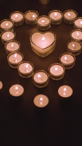 Vertical-Video-Of-Romantic-White-Candles-In-the-Shape-Of-A-Heart-On-Black-Background-1