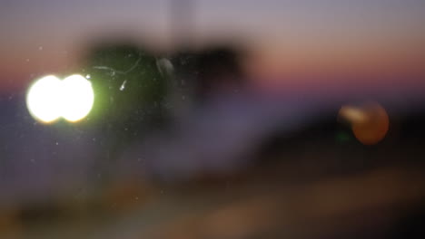 blurred cars driving with headlights on evening view through the glass