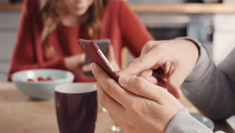 primer plano de una pareja usando dispositivos de teléfonos inteligentes desayunando en casa sin hablar antisocial